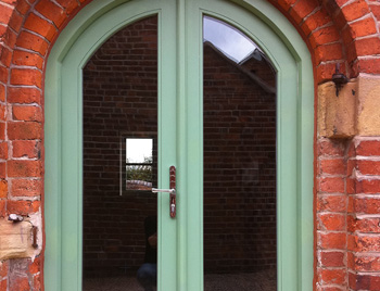 Wood table with porcelain mug, leather journal, brass pen, leather key ring, and a houseplant.